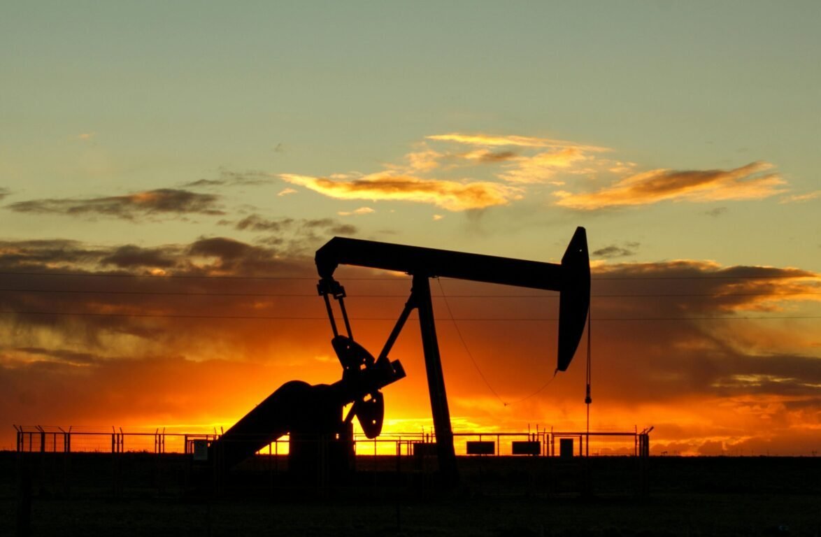 Dramatic silhouette of an oil pump jack against a vibrant sunset sky, emphasizing energy extraction.